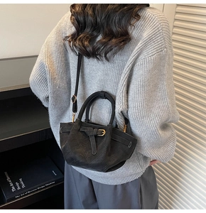 Detailaufnahme der schwarzen matten Ledertasche mit Rautensteppung am grauen Pullover