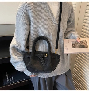 Model trägt eine schwarze gesteppte Ledertasche mit mattem Finish und Goldbeschlägen