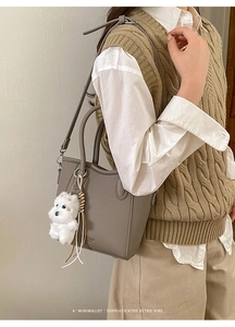 Détail du sac cabas en cuir grainé gris foncé avec un pendentif mignon en peluche blanche