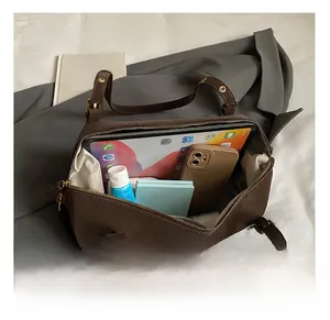 Detail view of large brown shoulder bag showing spacious interior with tablet and cosmetics
