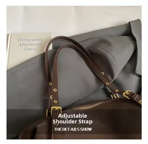 Detail of adjustable leather strap with gold grommets on a vintage dark brown tote bag
