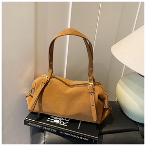 Detail of caramel leather shoulder bag with decorative eyelets and adjustable buckle strap