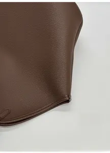 Detalle de la textura de cuero marrón con patrón litchi y costuras precisas en el bolso