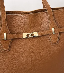 Close-up of brown litchi grain leather tote bag featuring gold clasp and precise stitching