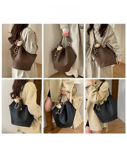 Detalle del bolso tote de cuero granulado con colgante de oso y lazo decorativo