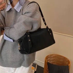 Detail of vintage black shoulder bag with matte texture and golden hardware accents