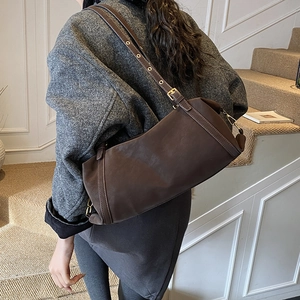 Detail of adjustable strap with metal eyelets on a dark brown leather cylinder bag