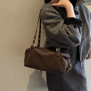 Detail of dark brown leather shoulder bag with gold eyelet straps and adjustable buckle