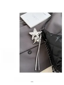 Close-up of silver star and heart charms with metallic tassels on black quilted bag