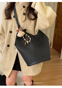 Detalle del bolso tote de cuero negro con letras de moda y colgante de oso peluche