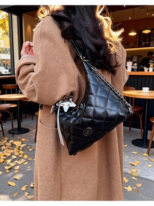 Close-up of black quilted tote bag with silver star pendant and fringe detail