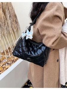 Detail of black quilted leather shoulder bag with silver heart charm and chain strap
