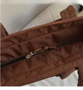 Detailed close-up of smooth metal zipper and woven puller on brown tote bag