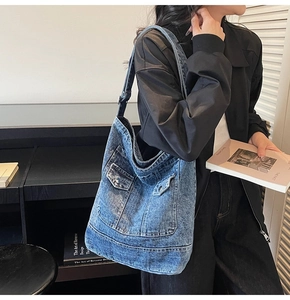 Détail du sac cabas en denim délavé bleu montrant la poche décorative et le bouton
