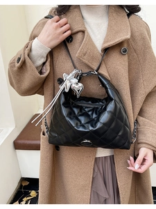 Close-up of black quilted shoulder bag with silver heart charms and chain strap detail