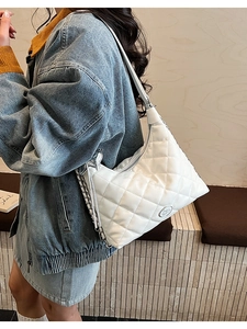 Detailed close-up of a white quilted shoulder bag with silver chain and metal logo