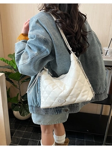 Detail showing white quilted leather tote with silver chain strap on model's shoulder