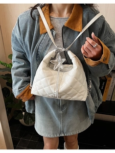 Close-up of a white quilted crossbody bag with a silver star pendant and sleek zip