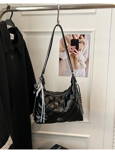 Close-up of black quilted leather shoulder bag featuring silver chain and tassel detail