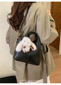 Λεπτομέρεια μαύρης δερμάτινης τσάντας κουβά με λευκό βελούδινο κουνελάκι σε ένα μοντέλο