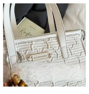 Gros plan du sac à main blanc tressé avec breloque en perles et anneaux en métal