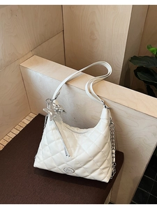 Detail of white quilted faux leather tote with silver star charm and chain strap