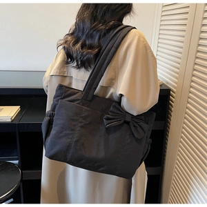 Side view of black large capacity nylon tote bag with side bow detail on shoulder