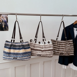 Three striped plush tote bags hanging on a rack in a minimalist fashion boutique setting