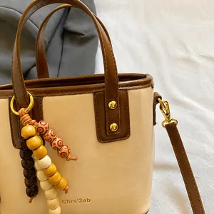 Détail des finitions dorées et du gland en perles de bois vintage sur le sac seau chic