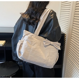Détail du grand sac cabas montrant le nœud décoratif élégant et la poche latérale pratique