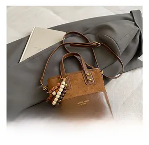 Détail d'un sac bandoulière rétro marron avec surpiqûres en daim et perles en bois
