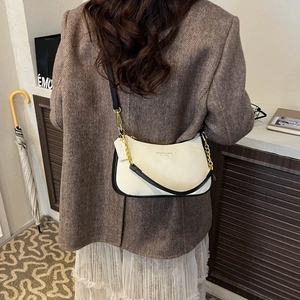 Detailed back view of a beige leather crossbody bag with gold chain strap on a model