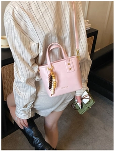 Détail du sac seau rose avec lettrage doré et charms décoratifs en perles de bois