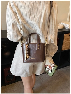 Detail of dark brown mini bucket bag showing lychee grain texture and wood bead decor