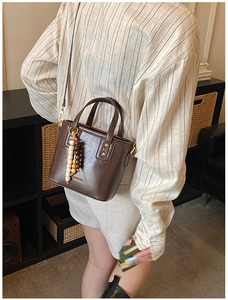 Détail du sac seau marron rétro avec clous dorés et pendentif en perles colorées
