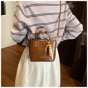 Detailed view of a vintage brown bucket bag with colorful wooden beads on a model