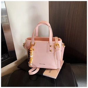 Detail view of pink leather bucket bag featuring gold hardware and a wooden bead charm