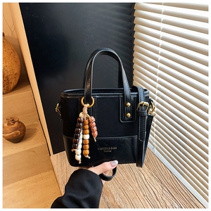 Détail du sac cabas en cuir noir avec pompon en perles vintage et boucle dorée