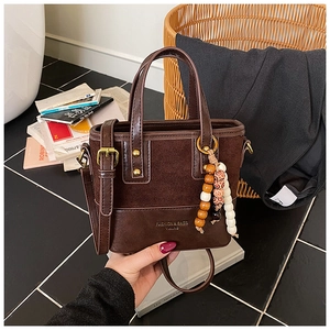 Détail du sac seau rétro en cuir marron avec imprimé mode et breloque en perles