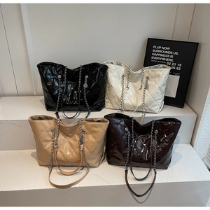 Quilted tote bags in black, white, khaki and brown displayed on elegant white steps