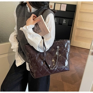 Detail of burgundy patent leather tote bag with quilted pattern and chain strap