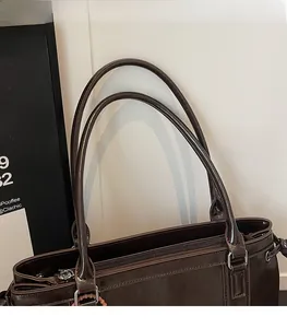 Detail der flexiblen Doppel-Schultergurte und des silbernen Reißverschlusses am braunen Shopper