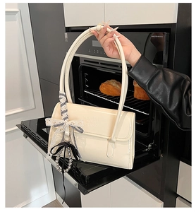 Dettaglio borsa in vernice bianco crema con fiocco e ciondolo di perle in cucina