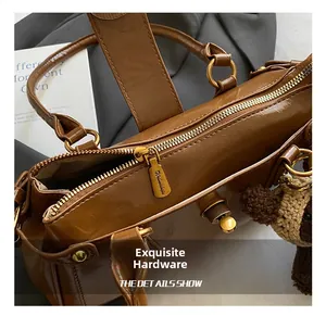 Detalle de bolso de cuero marrón brillante con cremallera de latón y oso colgante