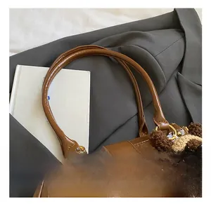 Detalle de bolso de cuero marrón vintage con cierre giratorio y colgante de oso