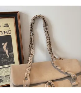 Detail of beige suede tote bag with woven shoulder strap and silver metal rivet accents
