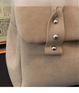 Detail of light brown suede tote bag with silver rivets and woven texture shoulder strap