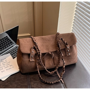 Detail shot of brown suede tote bag featuring woven handle and metal rivet accents
