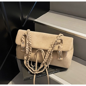 Detail of khaki suede tote bag featuring woven straps and silver metal stud accents