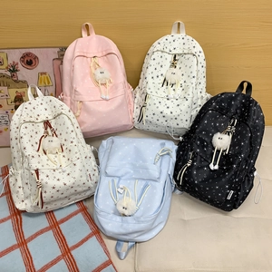 Détail de cinq sacs à dos colorés à motifs d'étoiles et jolis charms en peluche blanche